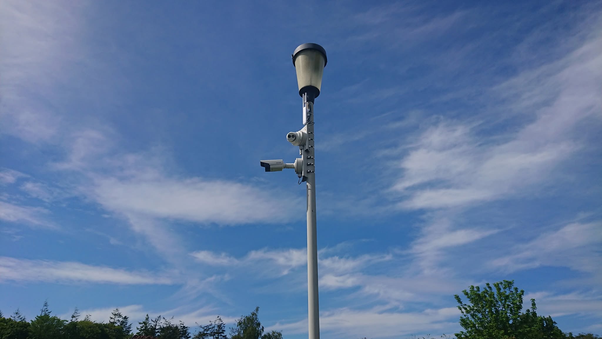 Outdoor CCTV cameras mounted on a lighting column against a blue sky